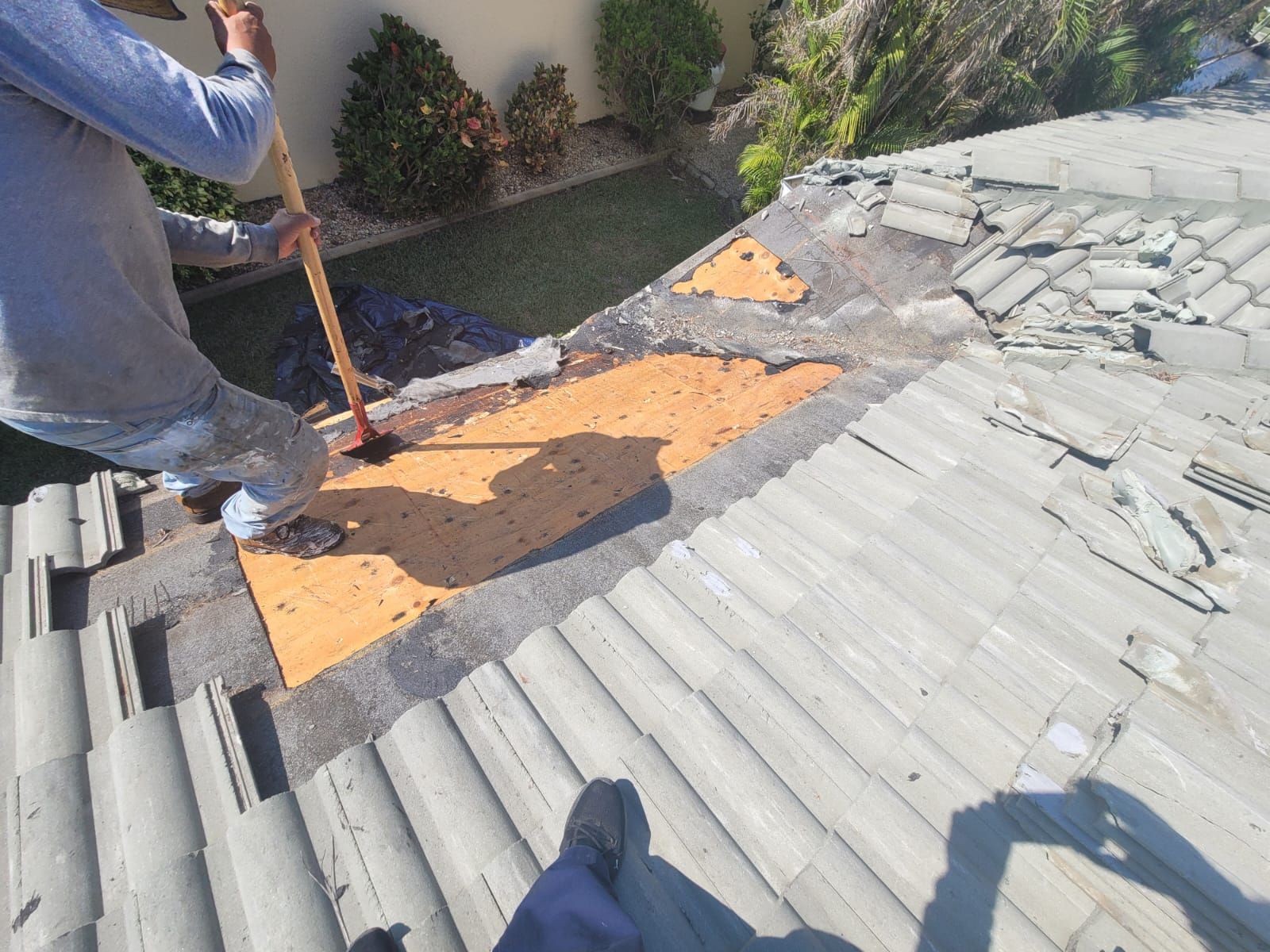 Crew repairing decking beneath removed roof tiles, Big Texas Roofing and Solar