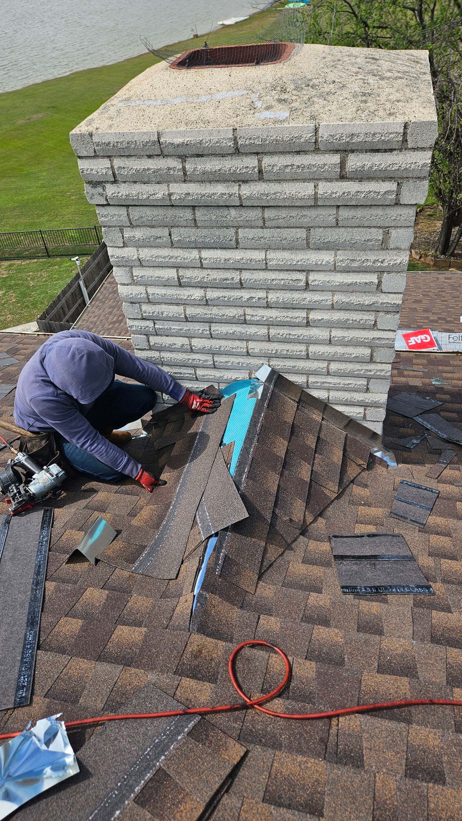 Roof repair crew beside a stone chimney, Big Texas Roofing and Solar