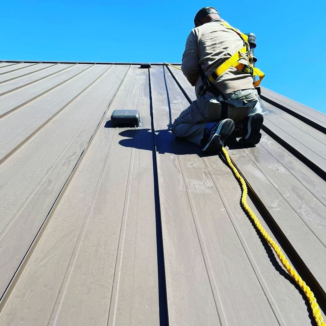 Roofer wearing a safety harness working on a metal roof from the Big Texas job gallery