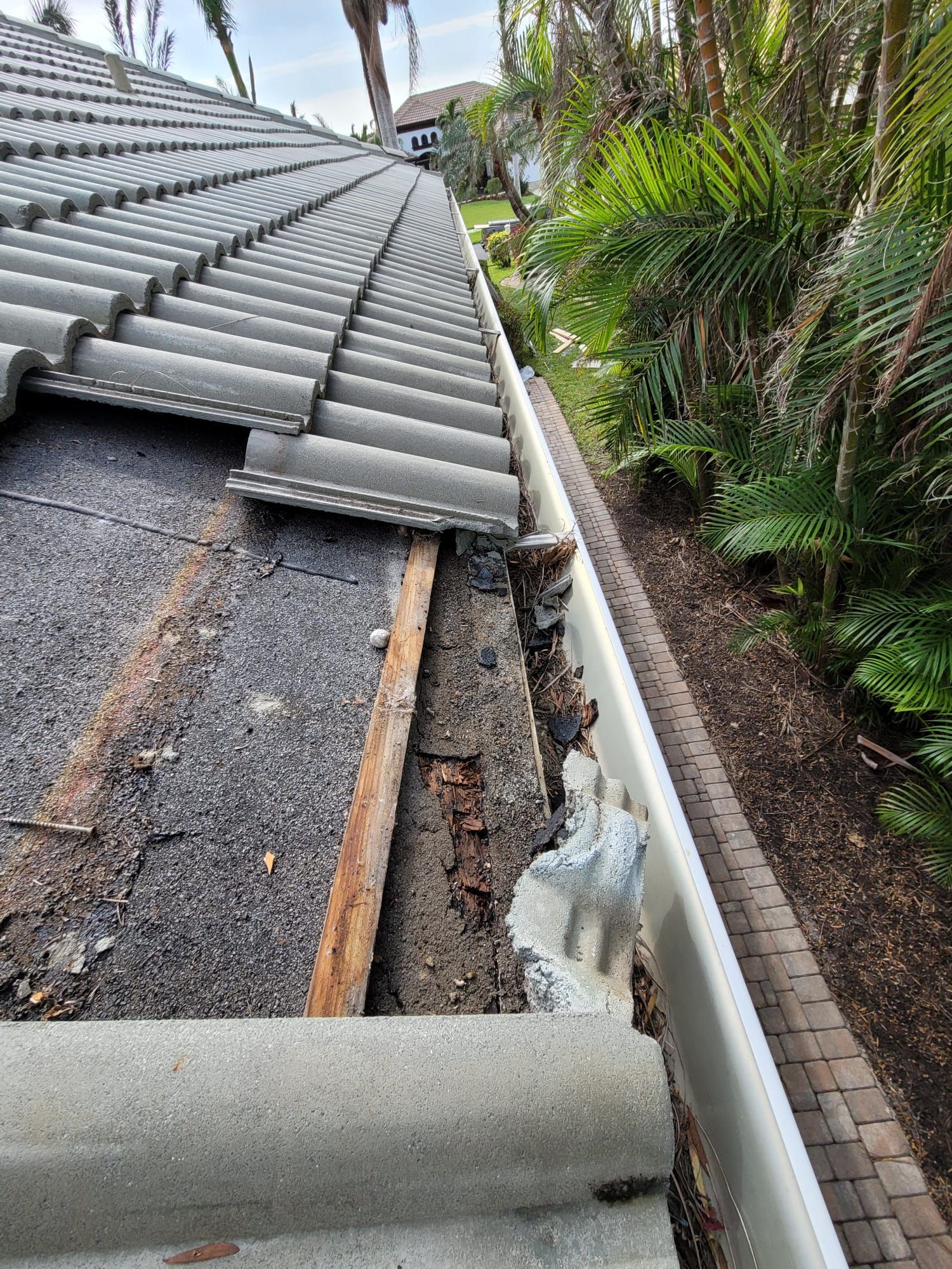 Damaged wood exposed beneath roof tiles, Big Texas Roofing and Solar