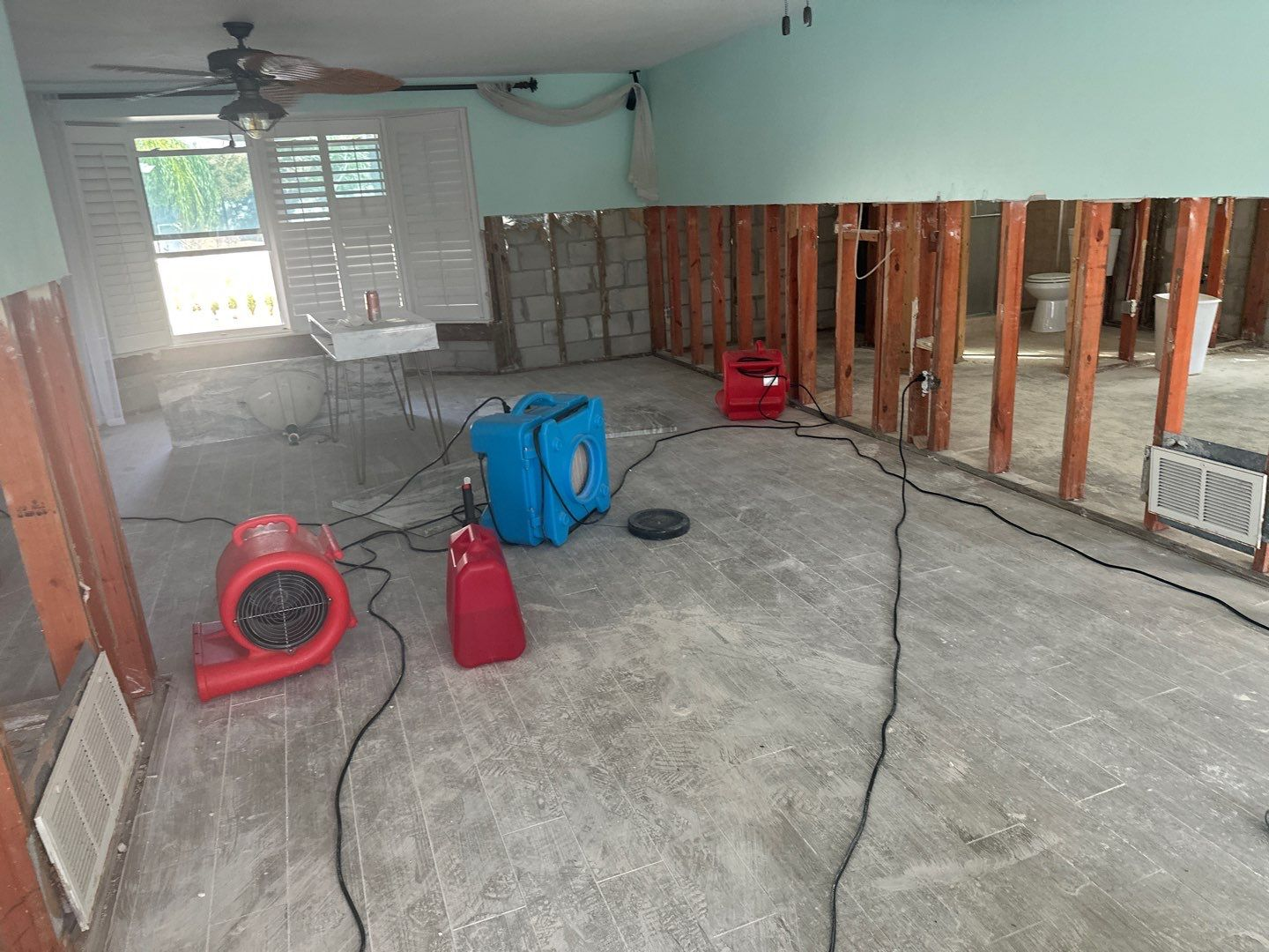 Air movers and drying equipment inside a flood damaged home with exposed wall framing